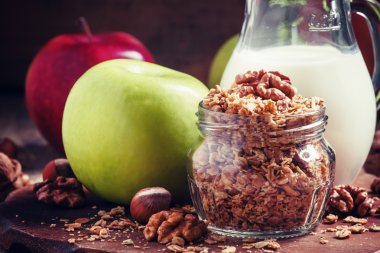 Baked muesli with nuts, milk jug, green and red apples