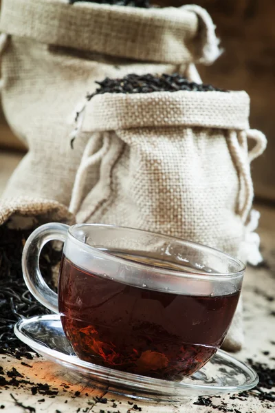 Copa de vidrio transparente de té negro y té seco en bolsas — Foto de Stock