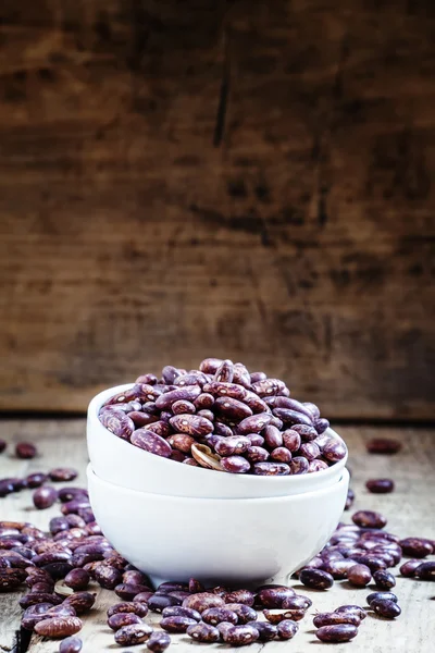 Фіолетово-коричнева суха квасоля в білій порцеляновій мисці — стокове фото