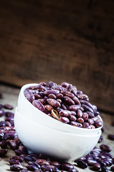 Purple-brown dry beans in a white porcelain bowl — Stock Photo, Image