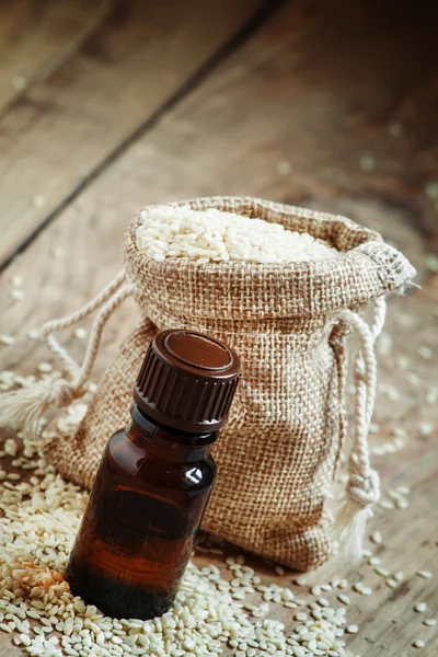 Aceite esencial de sésamo en una botella de vidrio marrón y semillas de sésamo — Foto de Stock