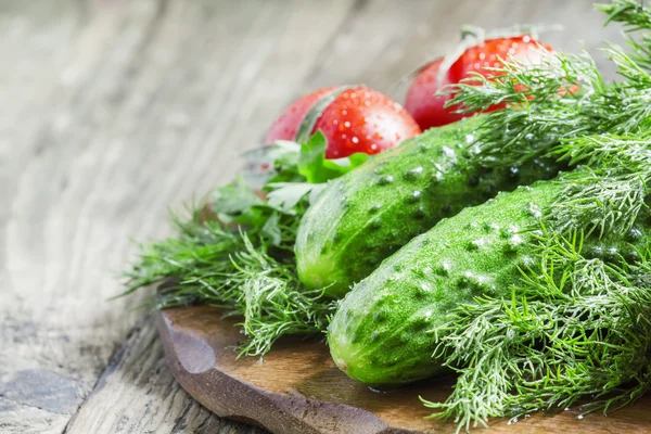 Verse komkommers, tomaten, dille en peterselie op de oude houten achtergrond — Stockfoto