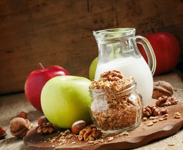 Muesli assado com nozes, jarro de leite, maçãs verdes e vermelhas — Fotografia de Stock