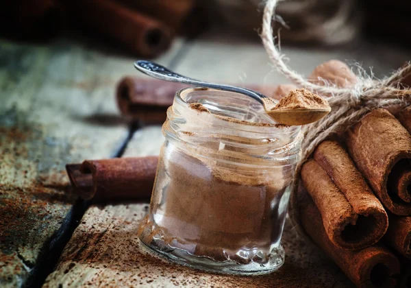 Canela moída em um frasco de vidro com uma colher — Fotografia de Stock