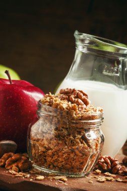 Baked muesli with nuts, milk jug, green and red apples