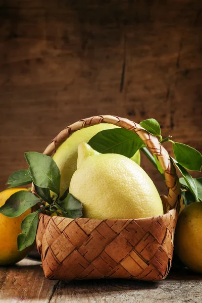 Limones frescos con hojas en una canasta de mimbre — Foto de Stock