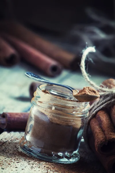 Ground cinnamon in a glass jar with a spoon — Stock Photo, Image