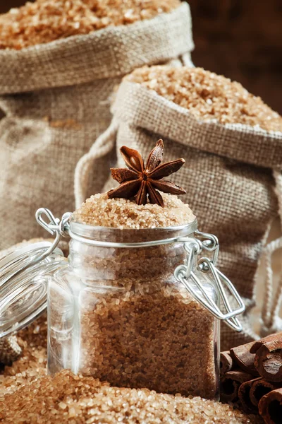 Коричневый тростниковый сахар в мешках из мешочка и стеклянная банка со звездой аниса — стоковое фото