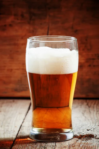 Large glass of light beer with foam on the old wooden background — Stock Photo, Image