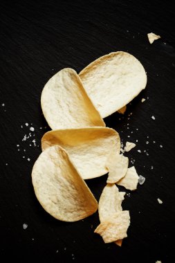 Büyük patates cipsi ile deniz tuzu karanlık taş zemin üzerine 