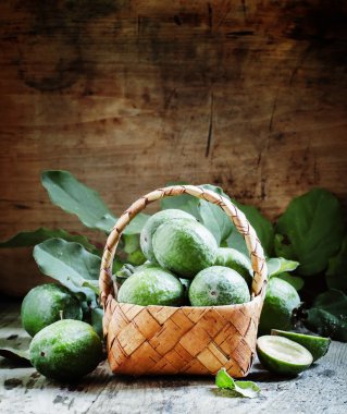 Ripe green feijoa fruits with leaves in a wicker basket  