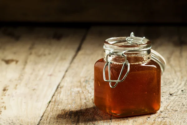 Янтарный темный мед в стеклянной банке — стоковое фото