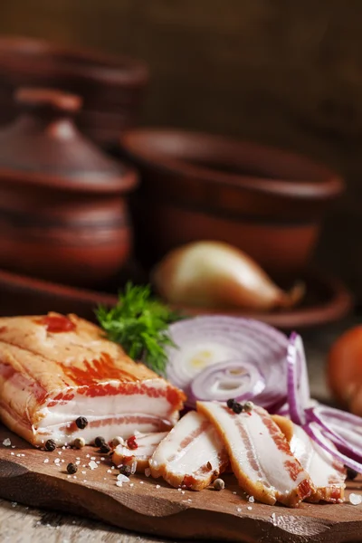 Panceta ahumada, cebolla roja, sal y pimienta en un plato de barro —  Fotos de Stock