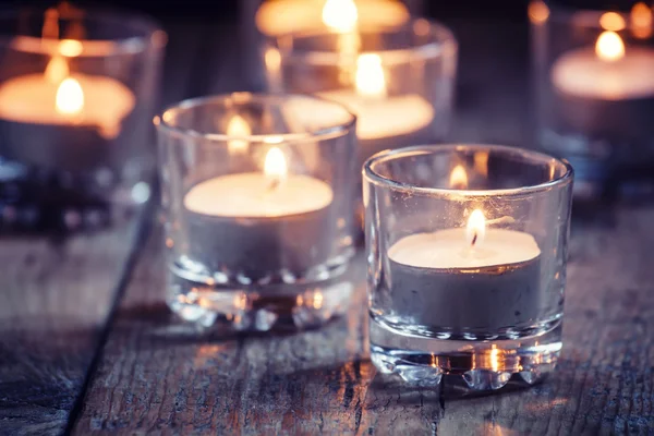 Горящие маленькие свечи в стеклянных подсвечниках — стоковое фото