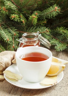 Black tea in a white cup with a lemon, ginger and honey  