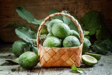 Ripe green feijoa fruits with leaves in a wicker basket  