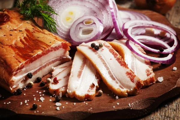 Smoked bacon, red onion, salt and pepper on a clay dish — Stock Photo, Image