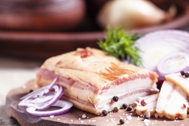 Smoked bacon, red onion, salt and pepper on a clay dish