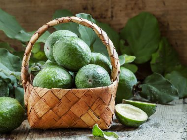 Ripe green feijoa fruits with leaves in a wicker basket  