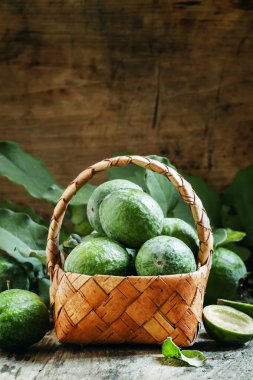 Ripe green feijoa fruits with leaves in a wicker basket  