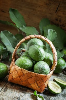 Ripe green feijoa fruits with leaves in a wicker basket  