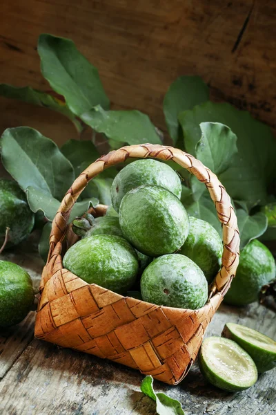 Ripe green feijoa fruits with leaves in a wicker basket — Stockfoto