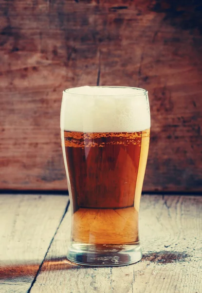 Large glass of light beer with foam on the old wooden background — Stock Photo, Image