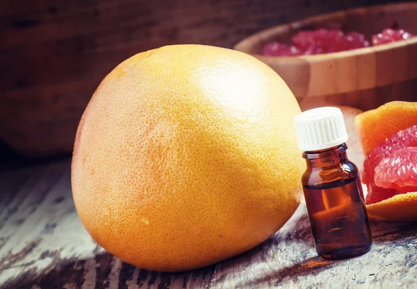 Óleo essencial de toranja em uma pequena garrafa e toranja fresca — Fotografia de Stock