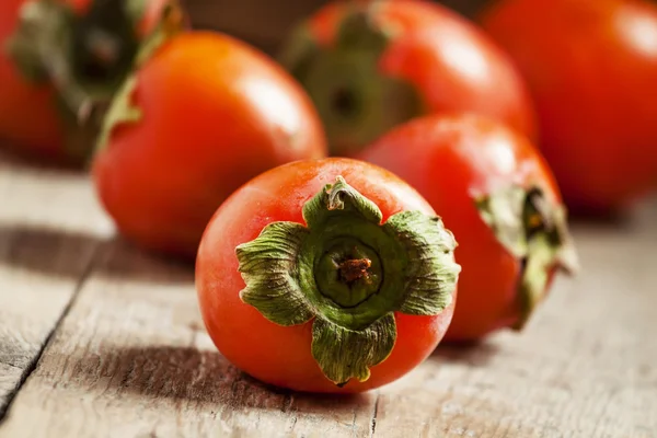 Ripe orange persimmons on an old wooden table — Stock Photo, Image