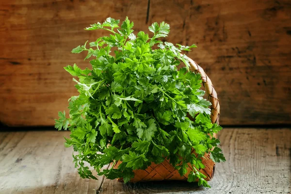 Bos van groene platte blad Italiaanse peterselie in rieten mand — Stockfoto