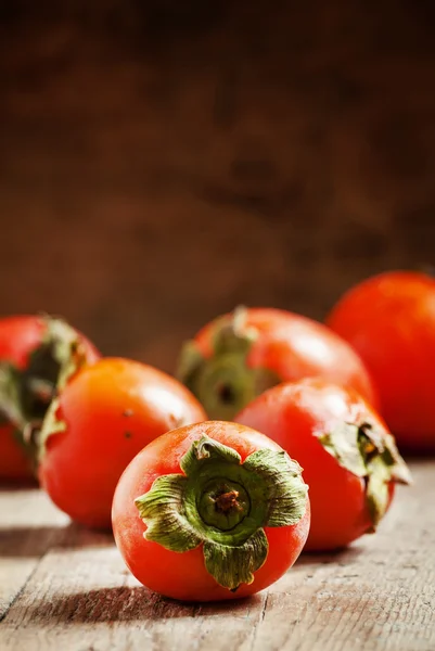 Dojrzały pomarańczowy persimmons na starym drewnianym stole — Zdjęcie stockowe