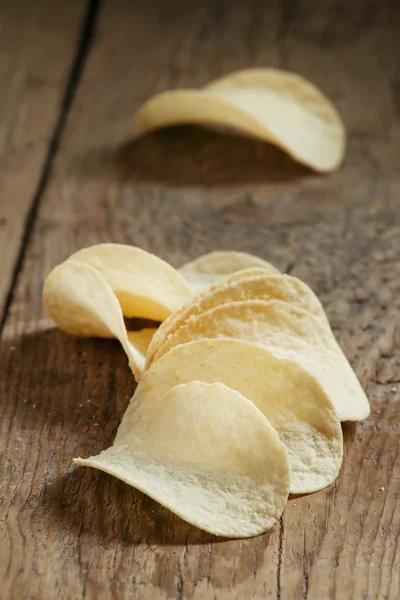 Golden potato chips and sea salt on the old wooden background — Stock Photo, Image