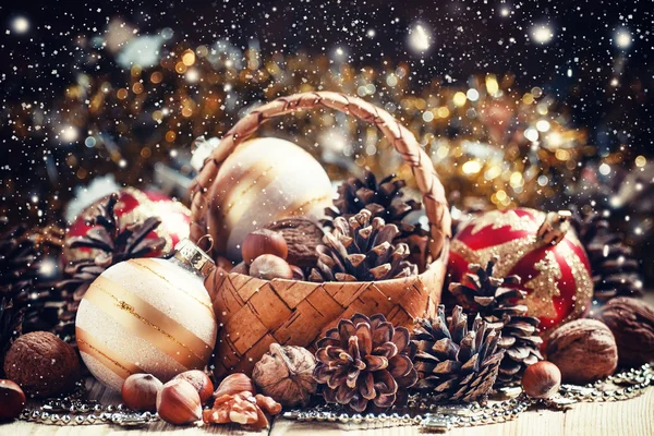 Cesta de mimbre con conos de abeto, nueces, bolas de Navidad, oropel y perlas — Foto de Stock