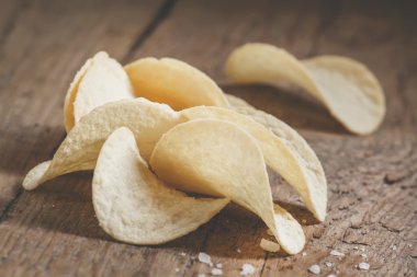 Altın patates cipsi ve eski ahşap arka plan üzerinde deniz tuzu 