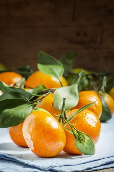 Čerstvé zralé mandarinky se zelenými listy na modrý ubrousek — Stock fotografie
