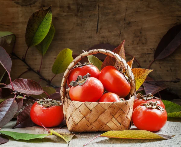 Ripe persimmons in a wicker basket — Stock Photo, Image