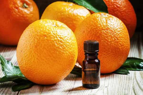 Óleo de laranja em uma pequena garrafa e frutas frescas — Fotografia de Stock