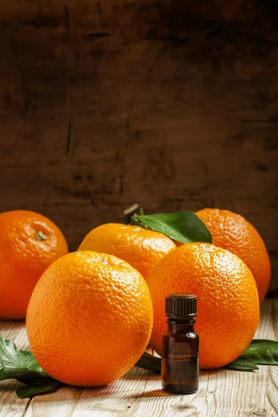 Óleo de laranja em uma pequena garrafa e frutas frescas — Fotografia de Stock