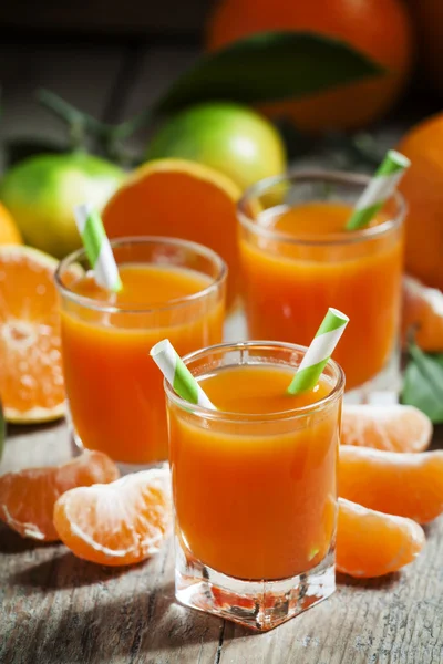 Fresh juice of ripe mandarins in a small glasses with striped straws — Stock Fotó