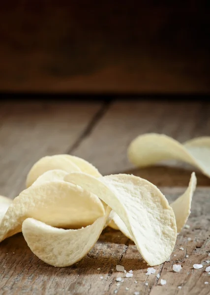 Goldene Kartoffelchips und Meersalz auf dem alten Holzgrund — Stockfoto