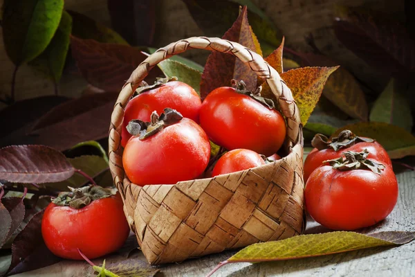 Ripe persimmons in a wicker basket — Stock Photo, Image
