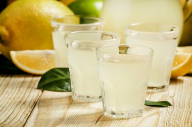 Home lemon liqueur and fresh lemons and limes   clipart