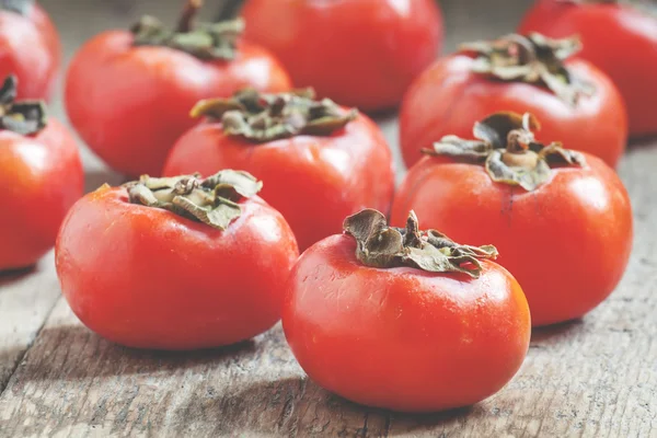 Small persimmons on the old wooden background — Stock Photo, Image