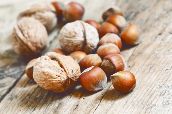 Nocciole e noci su un vecchio tavolo di legno — Foto Stock