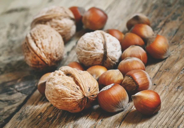 Haselnüsse und Walnüsse auf einem alten Holztisch — Stockfoto