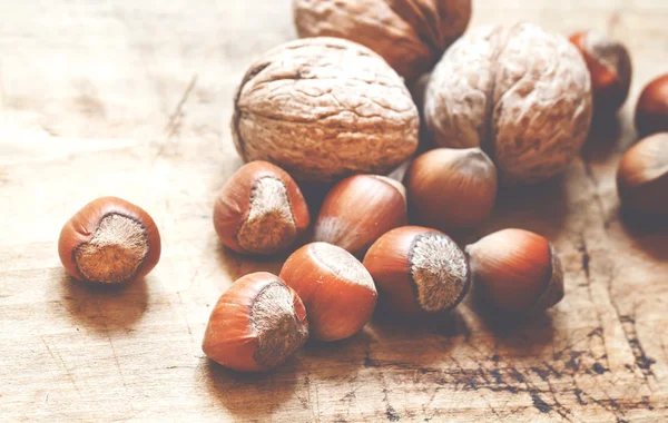 Nocciole e noci su un vecchio tavolo di legno — Foto Stock