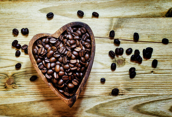 Arabica Coffee beans in a wooden bowl in the shape of a heart