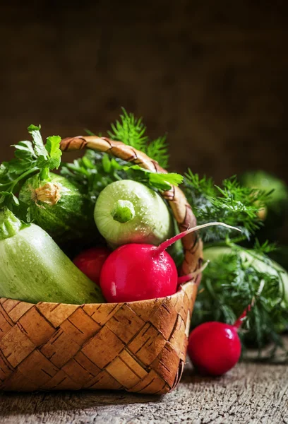 Wicker basket with a crop of spring vegetables and herbs — Stock Photo, Image