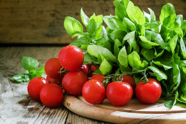 Черри помидоры, зеленый базилик, деревянный фон — стоковое фото