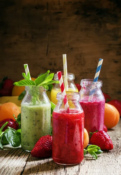 Разноцветные бутылки со свежими фруктовыми коктейлями — стоковое фото